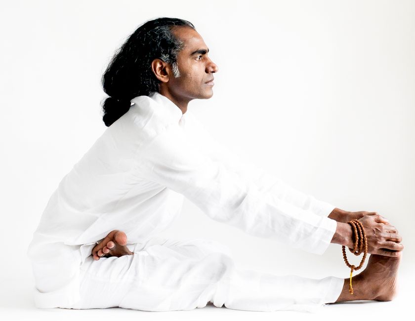 An Indian yogi practices seated forward bend asana, embodying mindfulness and calm.