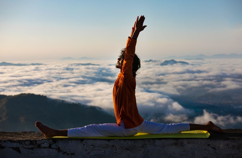 Serene yoga pose on a mountain edge above a sea of clouds at sunrise symbolizes mindfulness and peace.